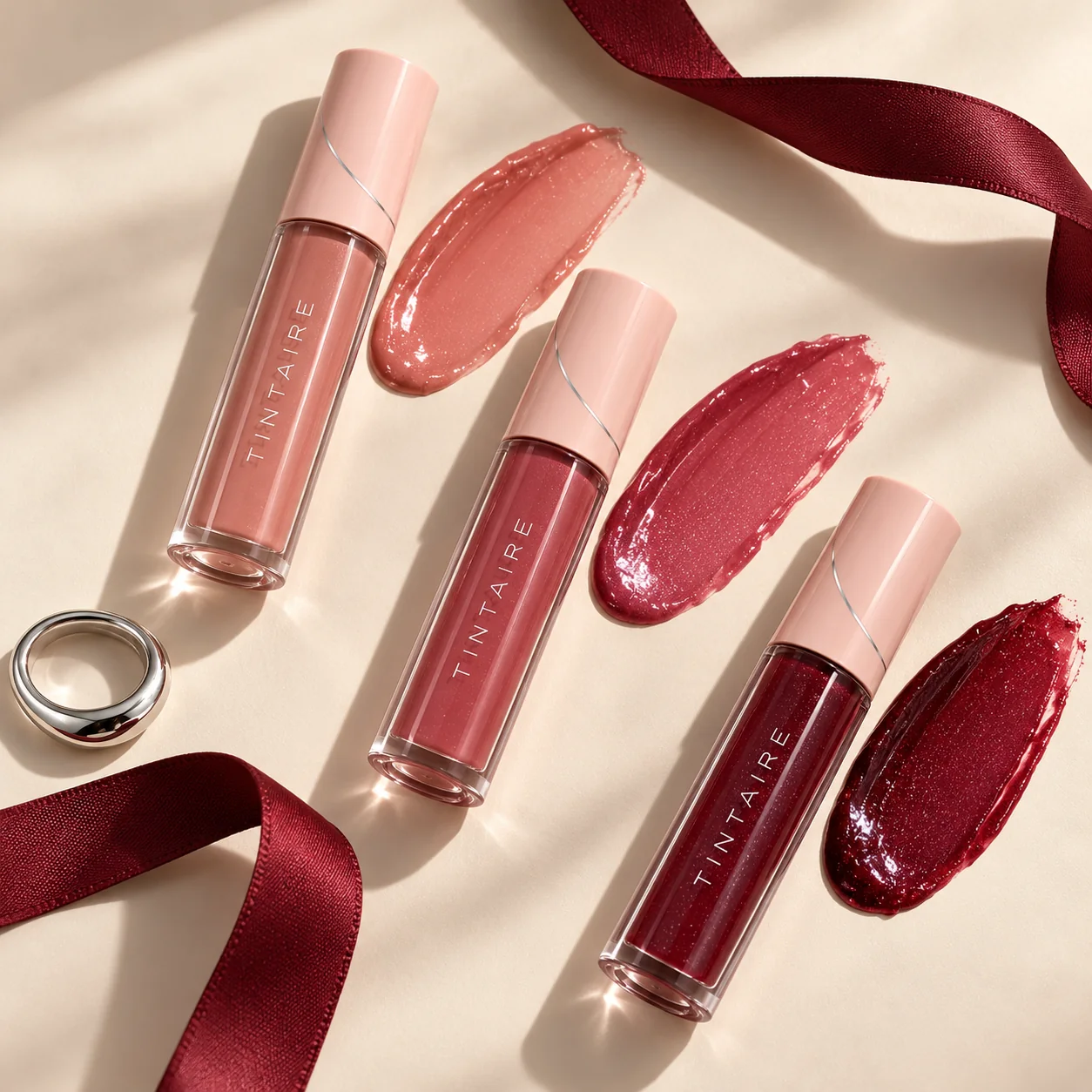 Three TINTAIRE lip glaze shades with matching colour swatches
